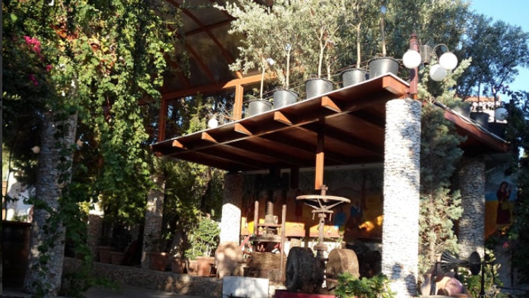 old stone grape press at Zahaios winery garden outside surrounded by treees